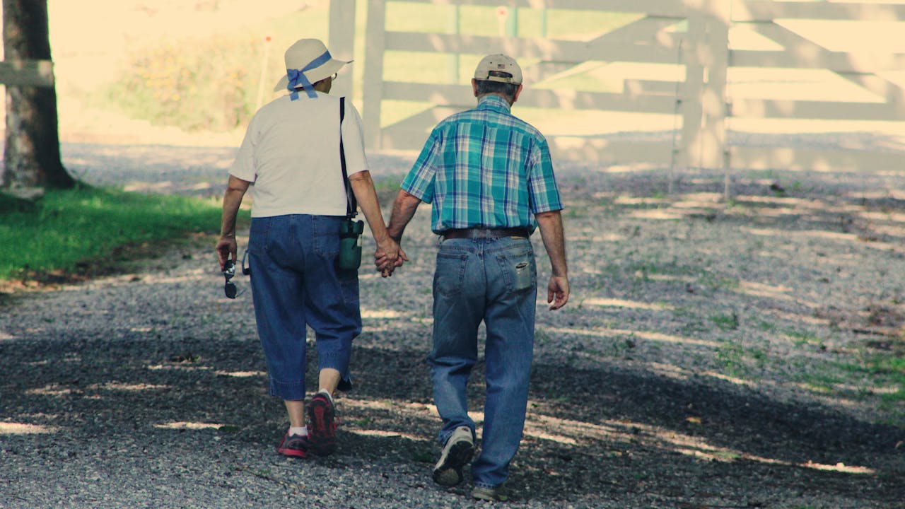Active older couple walking together outdoors in morning sunlight, staying healthy with longevity practices