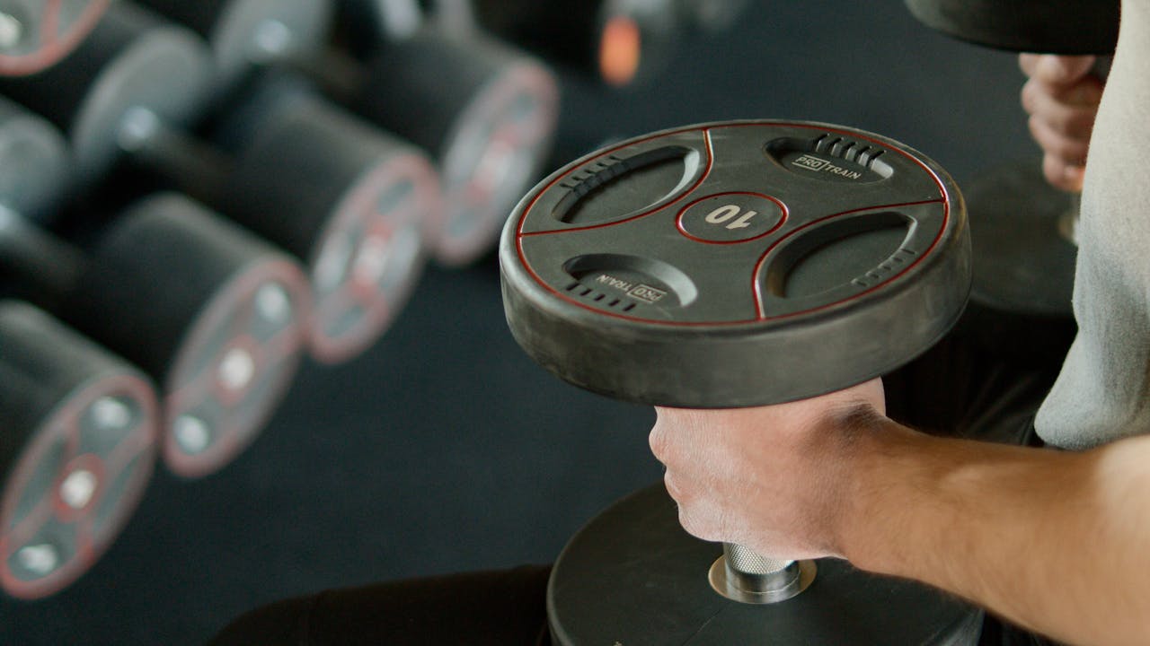 Person performing resistance training with dumbbells, supporting muscle mass and healthy aging