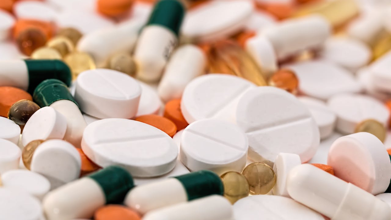 Supplement capsules and quality testing documents on a clean marble surface representing pharmaceutical grade standards