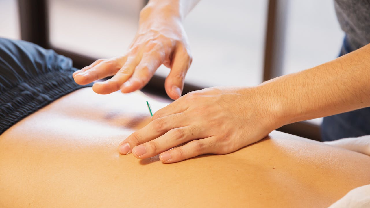 Person using a red light therapy panel device at home, warm glowing red light, clean modern wellness setting