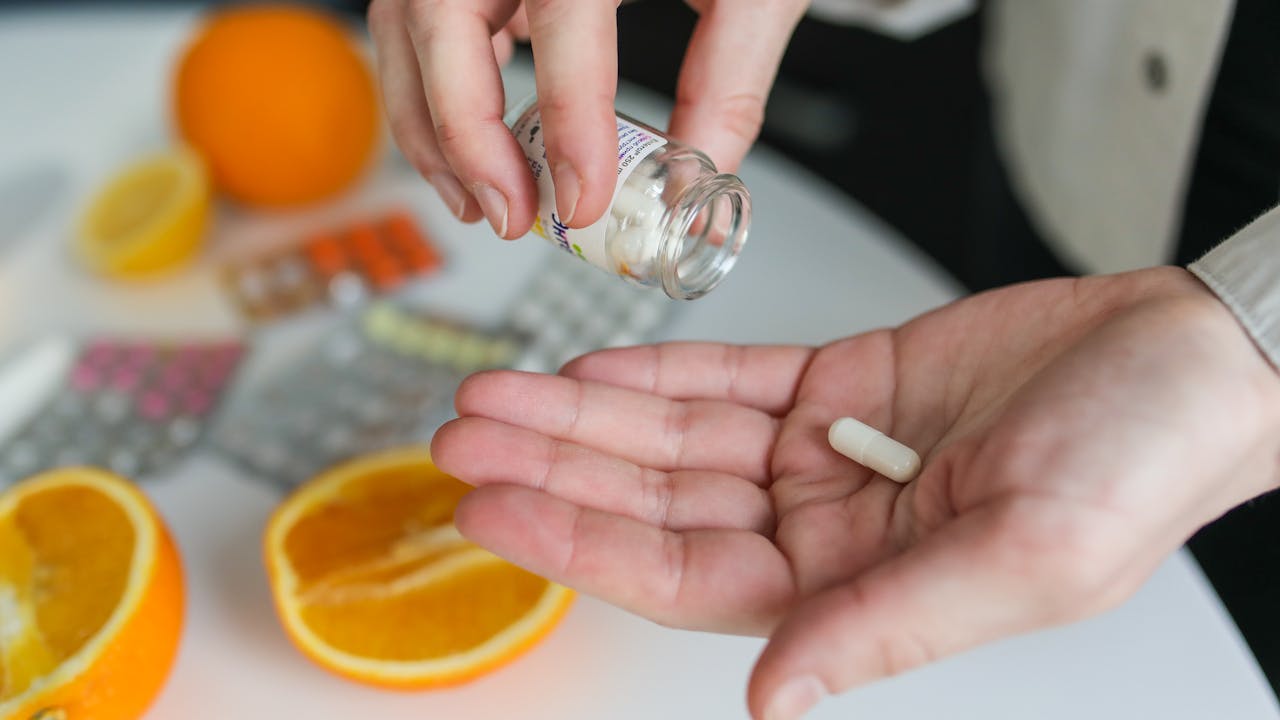 Supplement capsules and tablets arranged on a clean surface next to a glass of water