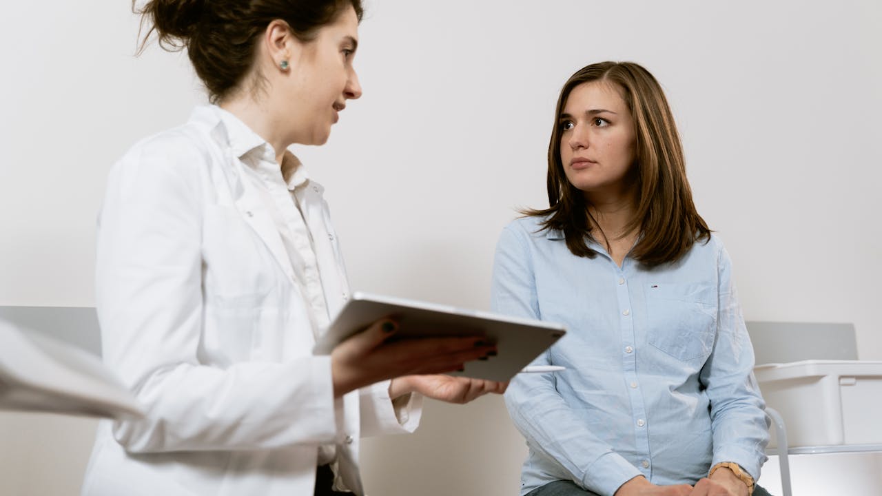 A doctor consulting with a patient via telehealth video call on a laptop